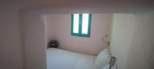 mały pokój z łóżkiem i oknem w obiekcie WabiSabi Serifos Chora w/ Spectacular Sea Views w mieście Serifos Chora