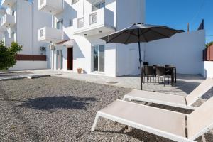 a white bench and an umbrella in front of a building at Casa Marinella in Gennadi