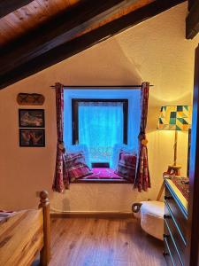 a bedroom with a window with a couch in front of it at Meizon - La Montagna, Pila, Crevacol, Aosta e Valpelline in Gignod