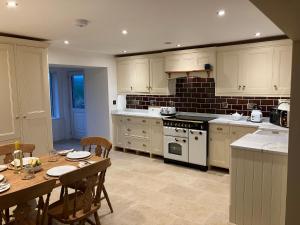 une cuisine avec des appareils électroménagers blancs et une table avec des chaises dans l'établissement Cherry Tree Cottage, à Stranraer