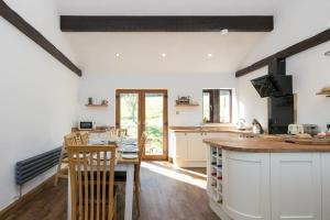 cocina con armarios blancos y mesa de madera en NEW BARN CONVERSION WITH PRIVATE HOT TUB, en Halifax