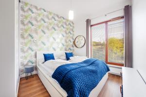 ein Schlafzimmer mit einem Bett mit einer blauen Decke und einem Fenster in der Unterkunft Apartamenty Sun & Snow Gdynia Nowe Orłowo in Gdynia