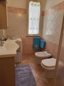 Un baño con lavabo, inodoro y ventana. en Casa Boi Dessena 1, en Orosei