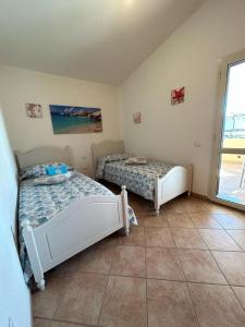 two beds in a room with a window at Casa Boi Dessena 1 in Orosei