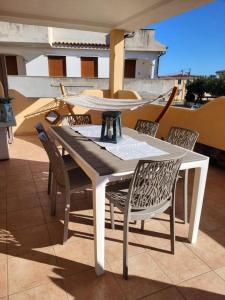 y balcón con mesa de comedor blanca y sillas. en Casa Boi Dessena 1, en Orosei