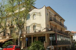 a building with a red car parked in front of it at Hotel Verudella in Rimini