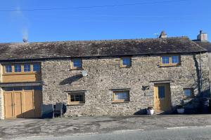 an old stone building with wooden doors and windows at 2 Malt Kiln Cottages in Grizebeck