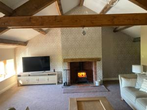 a living room with a fireplace and a tv at 2 Malt Kiln Cottages in Grizebeck
