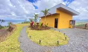 uma casa amarela no topo de uma colina com plantas em Vulkan Arenal Amazing View Lodge 4 WD em El Castillo de la Fortuna