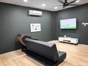 a living room with a black couch and a tv at Mekming Lodging - Homestay in Malacca