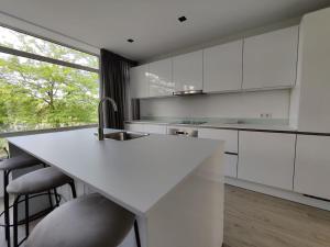 una cocina con armarios blancos y una barra con taburetes en K50169 Modern apartment near the center and free parking, en Eindhoven