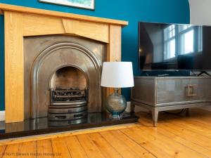 a living room with a fireplace and a lamp at Rosebery Place in Gullane