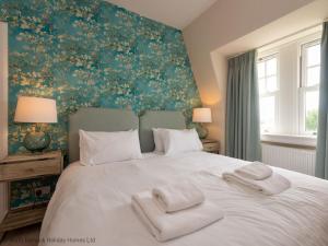 um quarto com uma cama branca com duas toalhas em Rosebery Place em Gullane