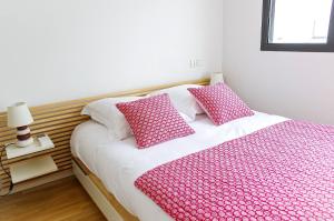 een slaapkamer met een bed met roze en witte lakens en kussens bij Belfort - Appartement 2 chambres avec ascenseur et Parking in Bordeaux