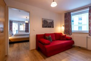 a red couch in a room with a bedroom at Pension Haus in der Sonne in Fieberbrunn