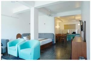 a bedroom with blue chairs and a bed and a kitchen at The Periwinkle Homestay Bhimtal in Bhīm Tāl