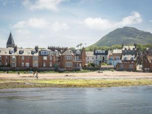a group of buildings on a beach with a mountain in the background at Southcot in North Berwick