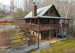 a house with a wrap around porch and a flag at Bucking Bison - Pet friendly, mountain view, hot tub, game room, fire pit and more! in Mineral Bluff