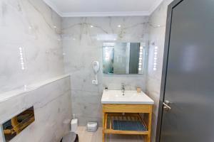 a white bathroom with a sink and a mirror at Delight Hotel in Ksamil