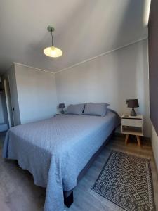Un dormitorio con una cama grande con una manta azul. en Departamento Ejecutivo Concepción, en Concepción