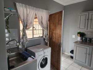 une buanderie avec un lave-linge et une fenêtre dans l'établissement Apartment at Kitchener, à Middelburg