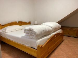 un lit en bois avec des draps blancs et des oreillers dessus dans l'établissement Casa vacanze Il Melograno, à Tremosine