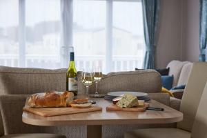 una mesa con una botella de vino, pan y copas de vino en Nirvana Coastal Retreat Holiday Home, en Cayton 37 fotos más