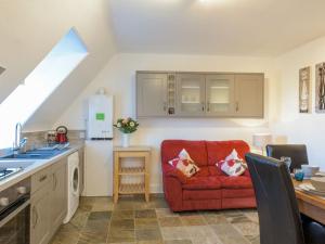 a living room with a red couch in a kitchen at Goose Green View in Gullane
