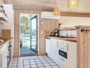 a kitchen with white cabinets and a sliding glass door at 8 person holiday home in Juelsminde in Sønderby