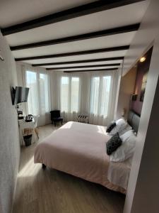 a bedroom with a large white bed and large windows at Hotel Aragon in Perpignan