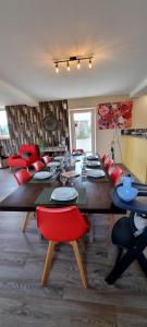 a dining room with a long table and red chairs at Mon Pré Vert in Saint-Ellier-du-Maine