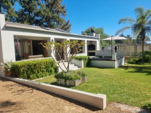 una casa blanca con un pequeño árbol en el patio en Alimandi Nursery Cottage, en Ciudad del Cabo