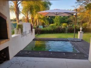 a pool with an umbrella next to a yard at Alimandi Nursery Cottage in Cape Town