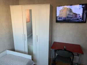 a bedroom with a desk and a tv on the wall at Jolie chambre Nenuphar dans belle maison in Vaulx-en-Velin