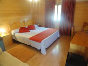 Un dormitorio con una cama con almohadas rojas. en Motel San Isidro, en Villarrubio