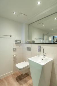 a white bathroom with a toilet and a sink at Hotel am Fischerstrand in Bansin