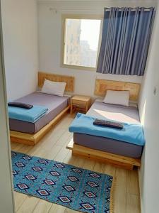 a room with two beds and a window and a rug at Champollion Hostel in Cairo