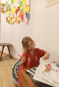 a little girl sitting at a table painting at Champollion Hostel in Cairo