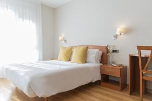 1 dormitorio con 1 cama blanca grande con almohadas amarillas en Hostal ALBA Lugo, en Lugo