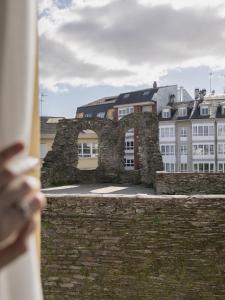 a person looking over a stone wall with buildings in the background at Hostal ALBA Lugo in Lugo