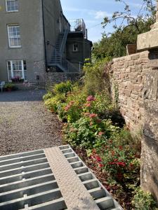 a house with a stone wall and some flowers at Top Floor at Cantref House in Brecon