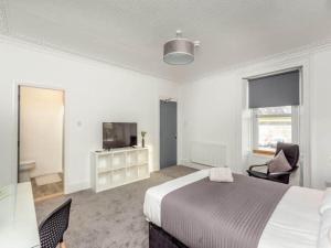 a white bedroom with a bed and a tv at LANGLEY LODGE 7 Double Bedrooms with SMART TVs, 6 Bathrooms, Fully Equipped Kitchen, Ample PARKING, Wifi, dishwasher, Garden, GREAT CENTRAL LOCATION Ideal for BUSINESS and TRADES TEAMS For Long Stays contact Langley Cottages & Serviced Apartments VAT reg in Wick