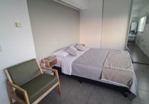 1 dormitorio pequeño con 1 cama y 1 silla en Infinito - Departamento con vista al mar en Comodoro Rivadavia