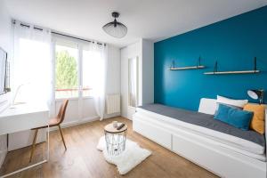 a bedroom with a blue wall with a bed and a desk at Life&Travel - Appartement Bordeaux - 4 chambres in Bordeaux