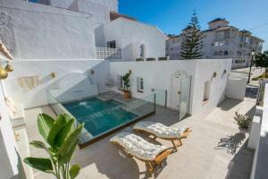 a villa with a swimming pool and two chairs at Marinero beach 2 in Torrox Costa