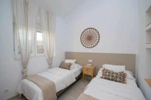 a bedroom with two beds and a clock on the wall at Marinero beach 3 in Torrox Costa
