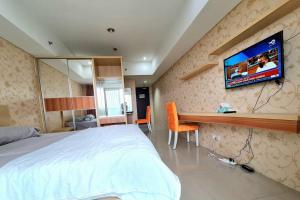 a bedroom with a bed and a tv on the wall at La Grande Merdeka Apartment in Bandung