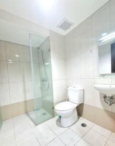 a bathroom with a shower and a toilet and a sink at La Grande Merdeka Apartment in Bandung
