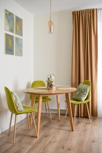 ein Esszimmer mit einem Tisch und grünen Stühlen in der Unterkunft Greenside SunPark Apartament in Przemyśl