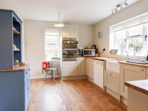 uma cozinha com armários brancos e piso em madeira em The Brambles em Colchester